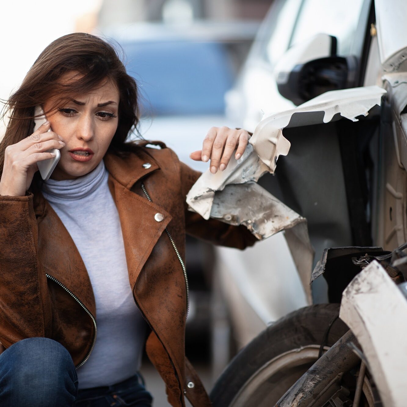 Sad woman calling roadside assistance after a car crash.