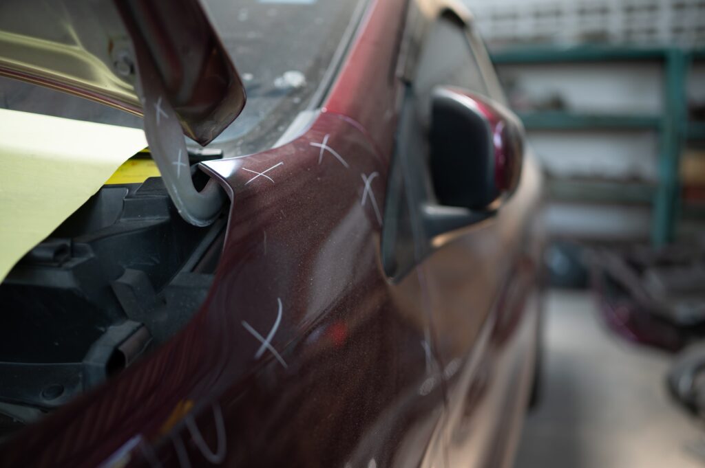 A car mechanic checks the condition of a car body to be repaired after a collision.